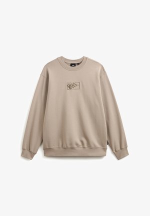 Beige sweatshirt met geribbelde ronde hals en boorden. Voorzien van een textuur Vans logo patch in het midden van de borst. Gemaakt van zachte stof.