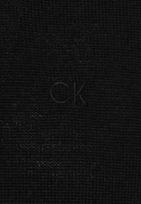 Černý texturovaný látkový pozadí s jemným reliéfem písmen "ck" ve středu.