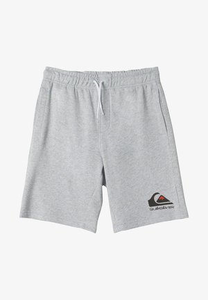 Dziecko ubrane w czarną, długorękawową koszulkę Quiksilver, szare spodenki z logo, białe skarpetki i czarne trampki Converse stojące na białym tle.