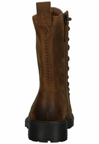 Bottine en cuir marron avec une fermeture éclair, bout rond, détails texturés sur les côtés et une semelle en caoutchouc noir. Des accents cousus mettent en valeur le design.