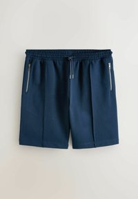 Mørkeblå træningsshorts med elastik i taljen, snøre og to lodrette lynlåslommer på forsidens sider.