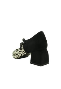 Zapato de tacón bloque en negro y blanco con estampado de lunares para mujer, con punta redonda y dos tiras con hebilla en el frente.