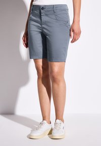 Šedé bavlněné šortky se slim fit, s knoflíkovým uzavíráním a kapsami. V kombinaci s bílými teniskami, které vytvářejí ležérní vzhled.