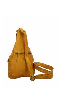 Geel leren schoudertas met een textuur, gebogen vorm, een ritszak aan de voorkant en een verstelbare schouderband. Bevat een leren merkpatch.