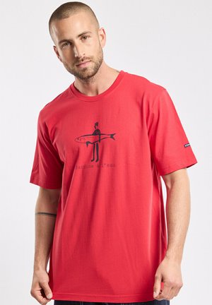 T-shirt en coton rouge avec un motif ludique représentant une personne tenant un poisson. Manches courtes, col rond et coupe décontractée.