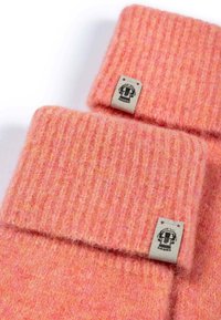 Weiche, rosa gerippte Wollbündchen mit umgeschlagenem Rand. Ausgestattet mit einem kleinen, grauen Stoffetikett mit schwarzem grafischem Detail.