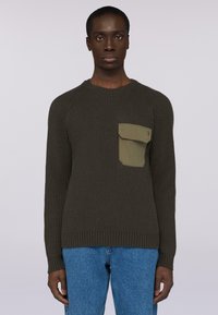 Tmavě zelený žebrovaný svetr s kulatým výstřihem a dlouhými rukávy, s přeloženou kapsou v světlejší zelené na levé části hrudi.