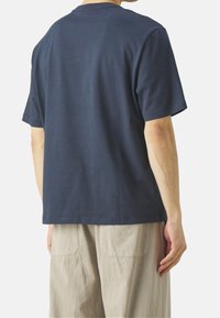 T-shirt in cotone blu navy con maniche corte, scollo rotondo e vestibilità comoda, visto da dietro. Design semplice, senza loghi visibili.