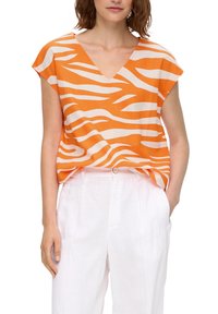Oranje shirt met korte mouwen en witte golvende strepen, met een V-hals ontwerp, gemaakt van lichte stof, gecombineerd met witte broek met een knoopdetail.