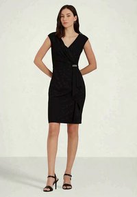 Črna oprijeta obleka s kratkimi rokavi, V-izrezom, ovitim dizajnom, stranskim draperjem in srebrnim zaponko. Gladko blago z rahlim sijajem.