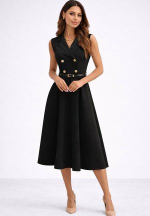 Femme portant une robe midi noire sans manches avec des boutons dorés croisés, une ceinture noire et des escarpins couleur chair, debout sur fond blanc.