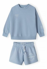 Ensemble de sweatshirt et short bleu clair en tissu doux. Le sweatshirt a des poignets et un col côtelés ; le short possède une taille élastique et un imprimé de logo.
