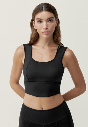 Zwarte sportbeha van glad, elastisch materiaal met een ronde halslijn en brede banden. Heeft naaideetails voor een aansluitende look.