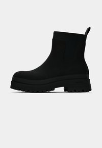 Svarta chelsea-boots med en stilren design, en gummisula med djupa mönster, en texturerad elastisk sidopanel och en dragflik för enkel påtagning.