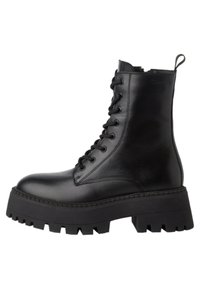Botín de tobillo negro de piel con cordones, con una suela de goma negra gruesa, que presenta un collar acolchado y una lengüeta para facilitar su calzado. Textura suave.