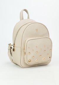 Zaino in finta pelle beige con design arrotondato, texture stampata e dettagli a borchie dorate sulla tasca anteriore. Due scomparti con zipper.