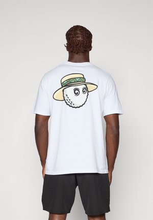 T-shirt blanc à manches courtes avec un dessin de balle de golf aux yeux en spirale et un chapeau de paille au dos. Le tissu est lisse. Shorts noirs.