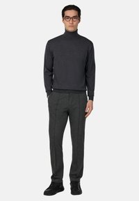 Tmavošedý rolák, slim-fit, v kombinácii s tmavošedými nohavicami s prednými záhybmi a čiernymi teniskami.