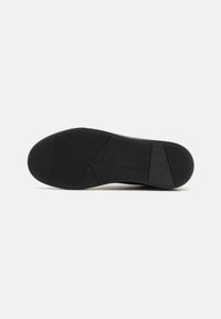 Black rubber shoe sole with a herringbone texture. Features varying traction patterns for grip and stability. Flat shape, no added accents.