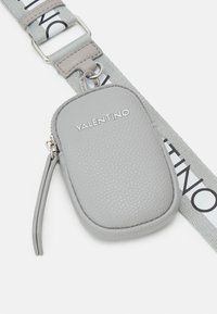 Bustina in pelle grigia testurizzata con chiusura a zip, con logo VALENTINO. È presente una tracolla di tessuto stampato in grigio con lettere a contrasto.