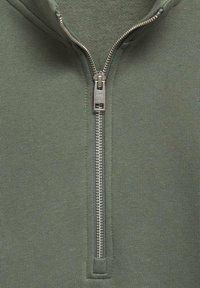 Felpa verde con zip e colletto alto, caratterizzata da una cerniera in metallo argento. Realizzata in un tessuto morbido con una finitura testurizzata.