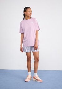 Hellblaues kurzärmliges T-Shirt, kombiniert mit weißen und blauen gestreiften Shorts. Die Schuhe haben rosa und weiße Akzente. Schlichte Gestaltung.