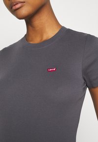 Grå t-shirt med korte ærmer lavet af blød bomuld med en tætsiddende pasform og rund hals; har et lille rødt Levi's-logo på brystet.