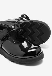 Zwarte gepatenteerde leren schoenen met een ronde neus, Mary Jane-bandje en een gestructureerde rubberen zool met een zigzagprofiel.