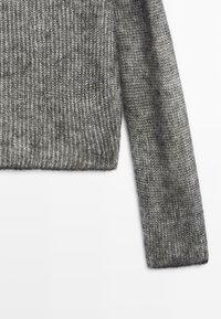 Grå strikket trøje med ribbet tekstur og lange ærmer, med en cropped længde og et blødt, vævet udseende.