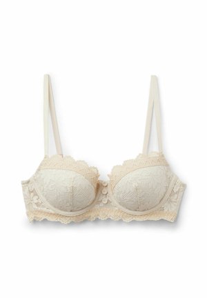 Soutien-gorge beige en dentelle avec armatures, bretelles réglables, motif floral, bords festonnés et trois boutons décoratifs au centre devant.