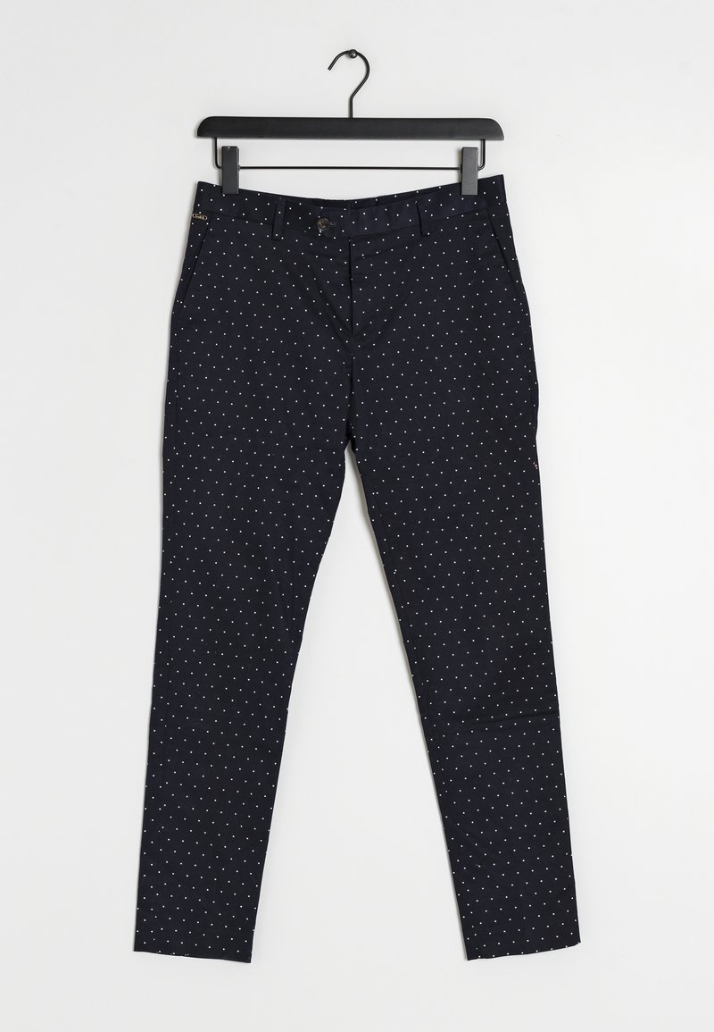 Pantaloni blu navy con pois bianchi, realizzati in un tessuto liscio, dotati di zip, passanti per cintura e tasche laterali. Appesi a una gruccia nera.