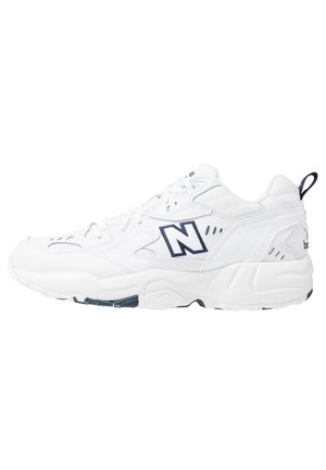 White New Balance sneaker with navy logo, lace-up design, and padded sole, shown in profile facing left on white background.