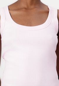 Lichtroze tanktop met een ronde hals, gemaakt van ribbelstof, met brede schouderbanden en een getailleerd ontwerp.