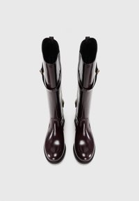 Botas de goma burdeos brillantes con forma recta, diseño alto, herrajes de acento dorado y suelas texturizadas para tracción.