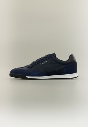 Navy blue low-top sneaker with black and white sole, lace-up front, and "GUESS" logo on side panel.