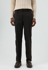 Donkerbruine op maat gemaakte broek met een gladde textuur, voorzien van een rechte snit en zijzakken, gecombineerd met bruine loafers.