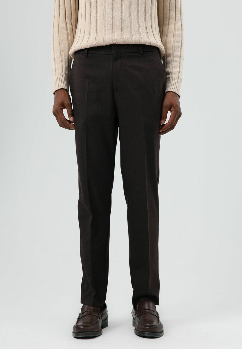 Donkerbruine op maat gemaakte broek met een gladde textuur, voorzien van een rechte snit en zijzakken, gecombineerd met bruine loafers.