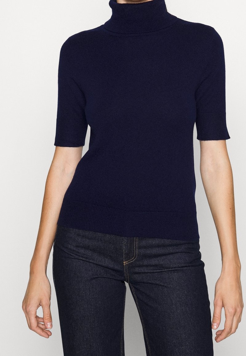 Námořnický rolák s krátkým rukávem z měkké pleteniny s přiléhavým střihem a žebrovanými okraji, v kombinaci s tmavými džínami.