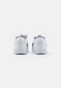 Sneakers bianche con tomaia in pelle liscia, colletto imbottito e tallone rinforzato. Presentano un logo swoosh nero di lato e marchiatura in rilievo.