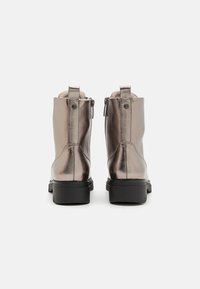Bottines métalliques argentées avec une texture lisse, bout rond et fermeture éclair à l'arrière, montant sur un talon noir.