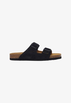 Sandalia deslizante de ante negro con dos correas ajustables, plantilla de corcho y suela de goma texturizada. Diseño clásico para uso casual.