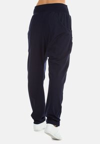 Navy blue jogger pants made from soft fabric; features a wide waistband, two large side pockets, and a relaxed fit with tapered cuffs.