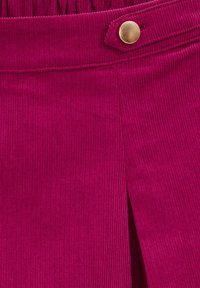 Fuchsia kordfløjlskørt med vertikale ribber, en sideslids og en messingknaplukning i taljen for ekstra detaljer.