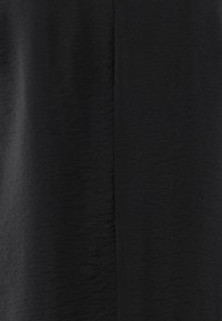 Svart tyg med en krusig textur, som har en subtil lyster. Slät yta med minimala sömmar, vilket skapar ett enkelt, elegant utseende.