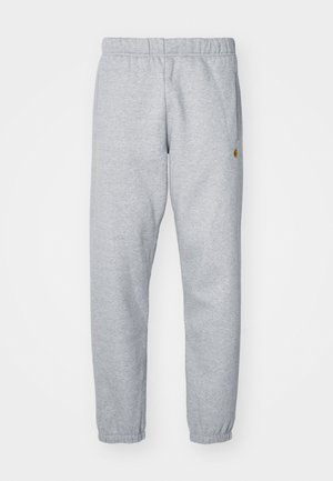 Pantalones de chándal grises hechos de una tela suave, con una cinturilla elástica, tobillos ajustados y un pequeño detalle de logo en el lado.