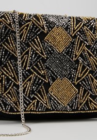 Perlebesat clutchtaske med en sort stoffbase, der har guld- og sølvgeometriske mønstre, en sølvkæde som rem og en tekstureret finish.
