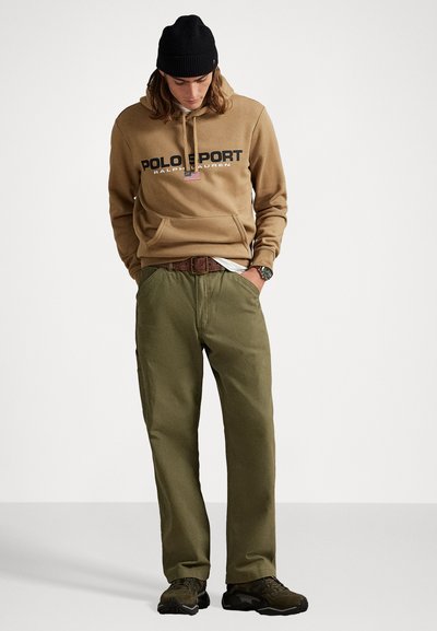 Hanorac khaki cu logo-ul "POLO SPORT", asociat cu pantaloni verzi măslinii, țesătură texturată, design casual și pantofi negri.