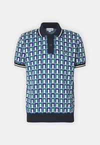 Kortärmad polo-tröja med ett geometriskt mönster i grönt, blått och vitt, med en marinblå krage och kontrasterande kant, två knappar och logotyp.