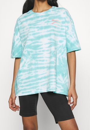 Sky blue tie-dye oversized t-shirt with short sleeves. Features a coral logo design on the left chest and a soft cotton texture.