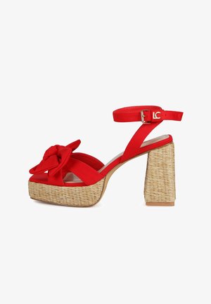 Sandalia de tacón alto roja con plataforma trenzada y tacón ancho, correa al tobillo con hebilla y lazo decorativo en la correa delantera.